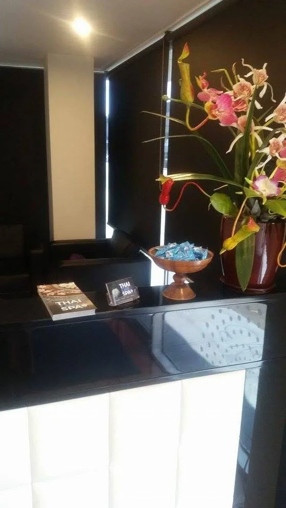Thai Day Spa reception — black desk, orchid, warm low light