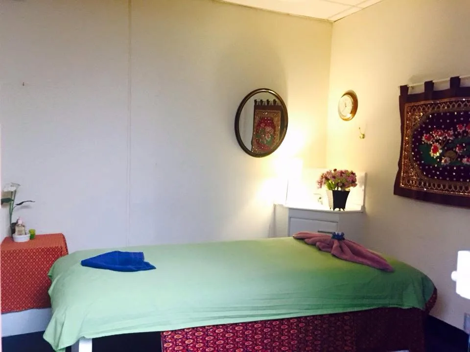 Treatment room — green-draped table, gold Thai silk wall hangings, warm lamp glow